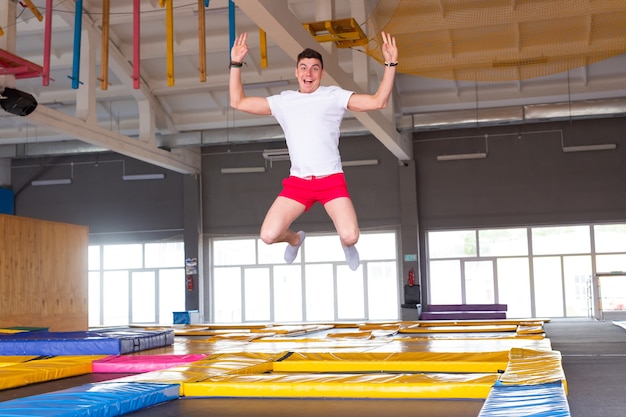 Freizeit, Sportspiele und Interessen - Lustiger junger Mann, der im Fliegenpark trampoliert.