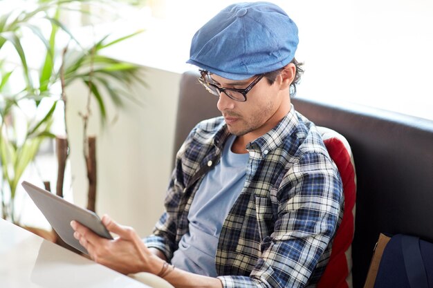 freizeit-, technologie-, kommunikations- und menschenkonzept - kreativer mann mit tablet-pc-computer, der am cafétisch sitzt