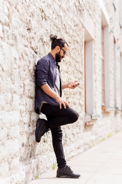 Freizeit-, Technologie-, Kommunikations- und Personenkonzept - Mann mit Sonnenbrille SMS-Nachricht auf dem Smartphone an der Steinmauer auf der Stadtstraße