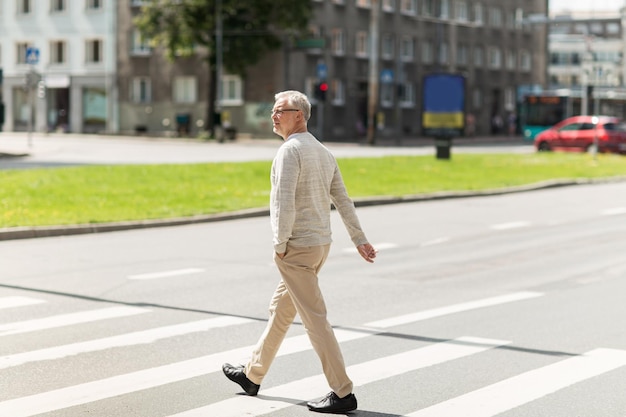 Freizeit- und Personenkonzept - älterer Mann läuft im Sommer über den Zebrastreifen der Stadt