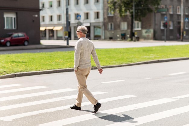 Freizeit- und Personenkonzept - älterer Mann läuft im Sommer über den Zebrastreifen der Stadt