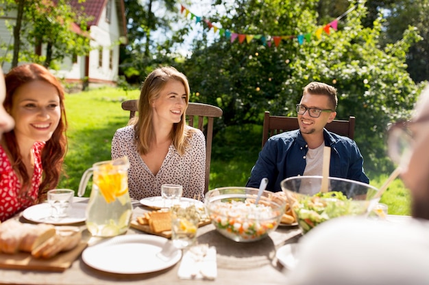Freizeit, Urlaub, Essen, Menschen und Essenskonzept – glückliche Freunde beim Abendessen auf der Sommergartenparty
