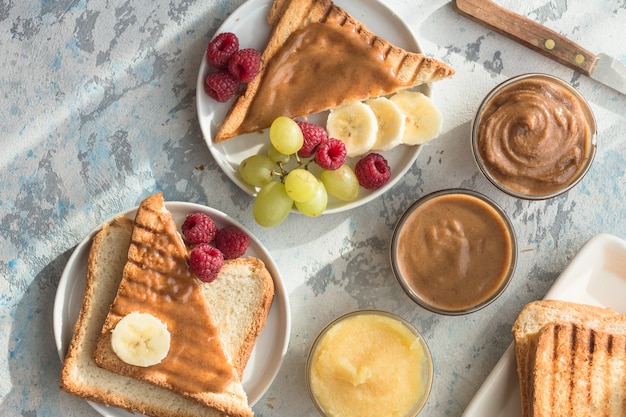 French Toast mit Mandelbutter und Früchten. Toastbrot mit Nussbutter. Hausgemachtes Toastbrot mit Marmelade und Erdnussbutter auf Holztisch zum Frühstück.