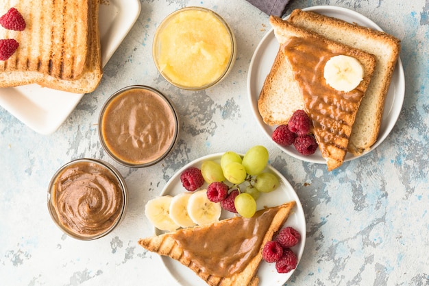 French Toast mit Mandelbutter und Früchten. Toastbrot mit Nussbutter. Hausgemachtes Toastbrot mit Marmelade und Erdnussbutter auf Holztisch zum Frühstück.