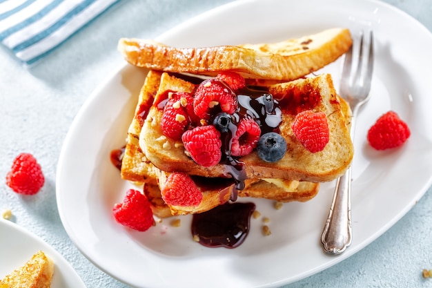 French Toast mit Sirup und Himbeeren zum Frühstück auf Teller serviert. Nahaufnahme