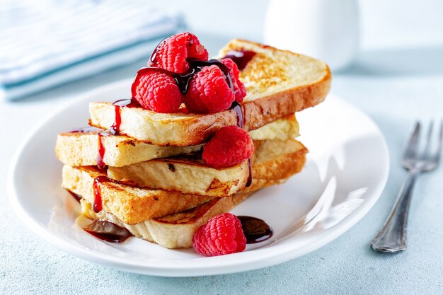 French Toast mit Sirup und Himbeeren zum Frühstück auf Teller serviert. Nahaufnahme