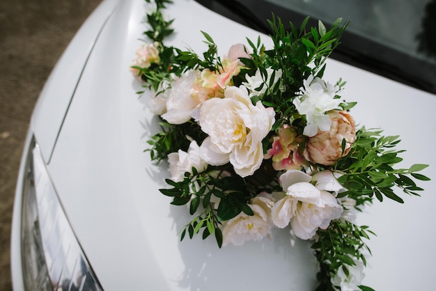 El frente de un automóvil decorado con flores el día de la boda de cerca