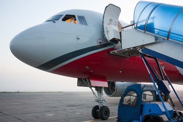 Foto frente del avión con puerta abierta y rampa de embarcadero cerca