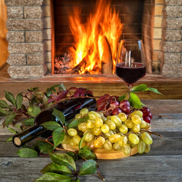 Frente a la chimenea en una noche de invierno un vaso de vino tinto y fruta