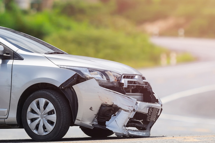 El frente del coche plateado se daña por accidente de choque en la carretera.