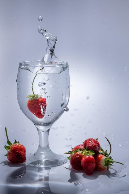 La fresa cae en un vaso de agua.