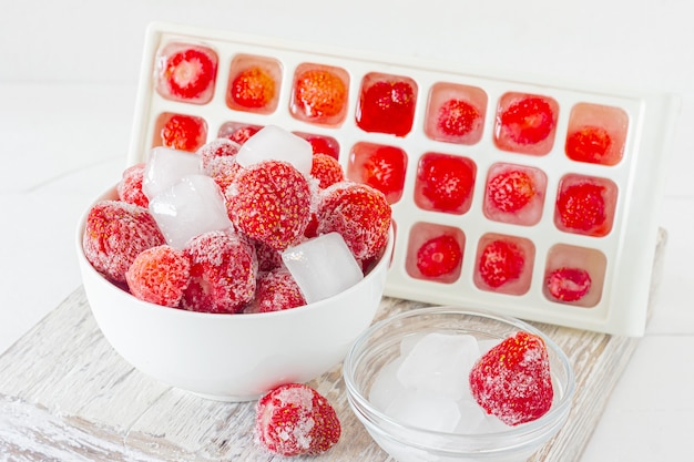 Fresa congelada con cristales de hielo sobre fondo rosa.