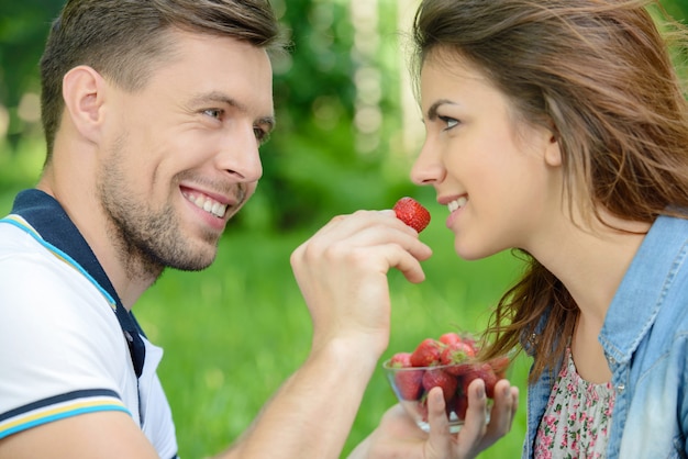 Fresa para ella. Hombres jóvenes alimentando a su novia