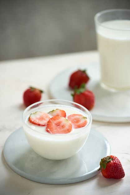 Fresa fresca en un vaso con postre yogur y fresa sobre fondo blanco.