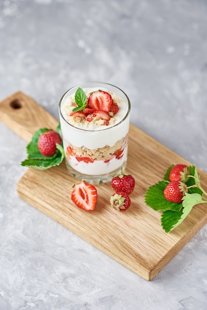 Foto fresa granola o batido en vidrio y bayas frescas en una tabla de cortar, vista superior