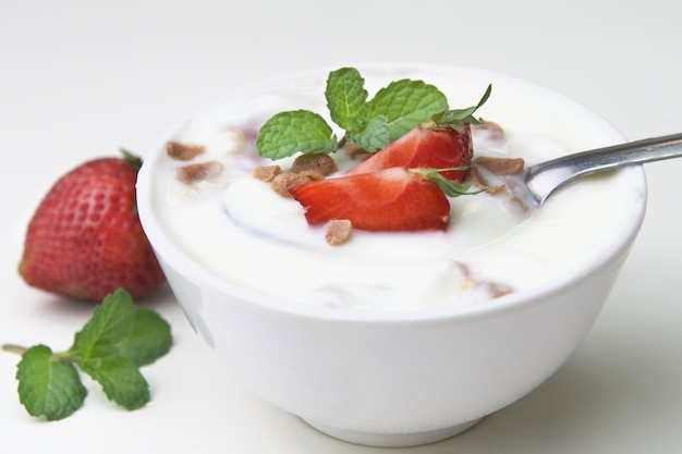 Fresa con yogur y menta en un tazón sobre fondo de madera