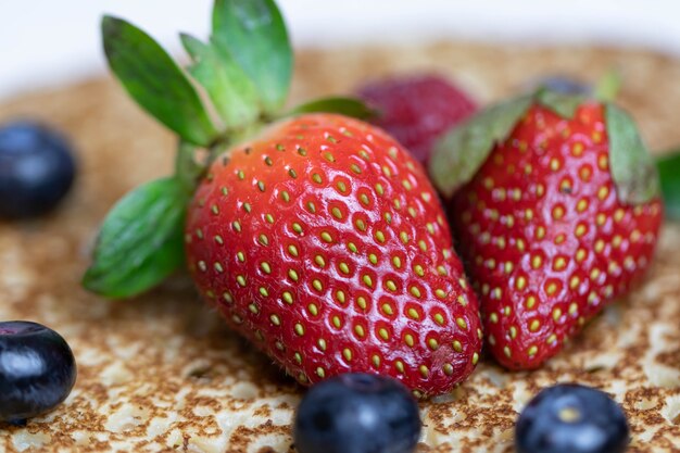 Fresas y arándanos maduros y jugosos se encuentran en un delicioso panqueque. Bliny plato nacional de la cocina rusa con frutos rojos frescos.