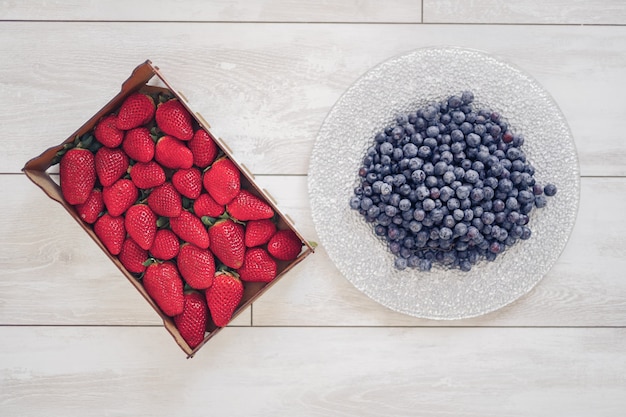 Fresas en una caja y arándanos en un plato