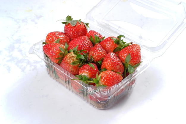 fresas en caja de plástico transparente sobre fondo blanco