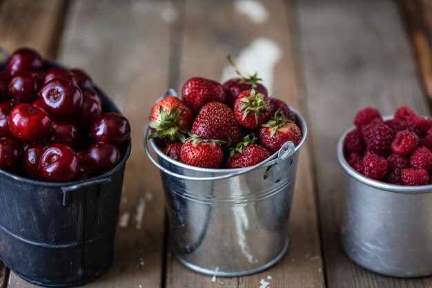 Fresas, cerezas, frambuesas en cubos sobre una mesa de madera