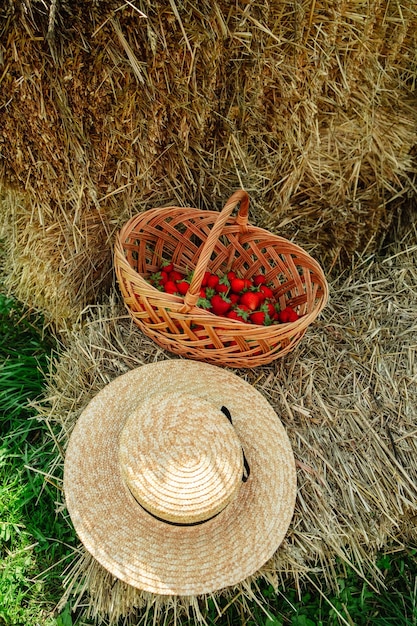 Fresas en cesta y sombrero de paja en pajar