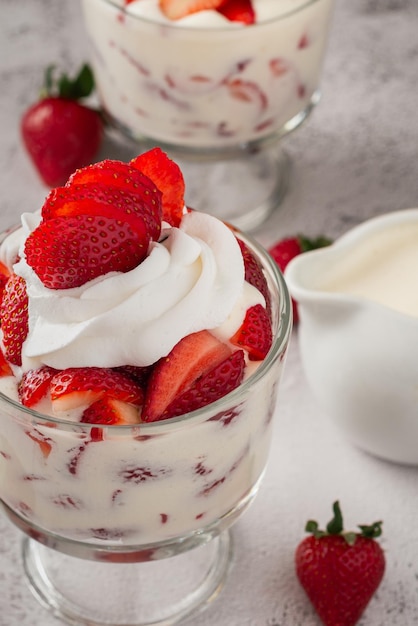 Fresas con crema en una taza de vidrio en una mesa de cemento