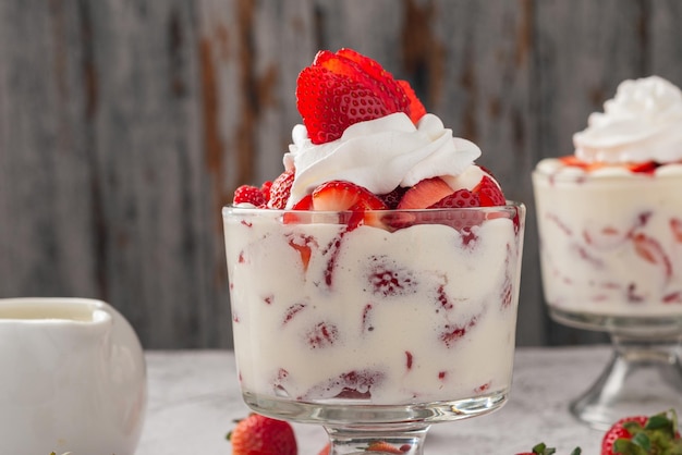 Fresas con crema en una taza de vidrio en una mesa de cemento