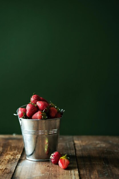 Fresas en un cubo de metal Fresas frescas en un recipiente sobre una mesa de madera