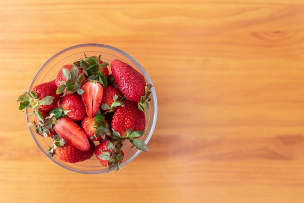 Fresas deliciosas y apetitosas en un recipiente de vidrio en la mesa de madera.