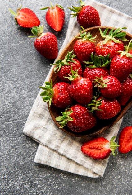 Fresas deliciosas maduras frescas en un recipiente blanco sobre un fondo de piedra gris