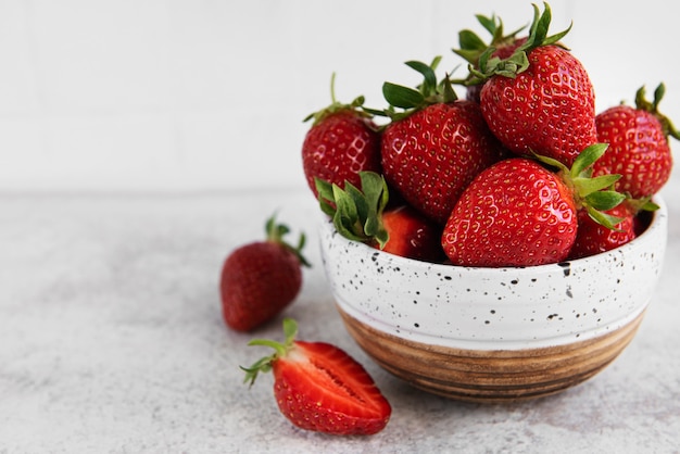 Fresas deliciosas maduras frescas en un recipiente blanco sobre un fondo de piedra gris