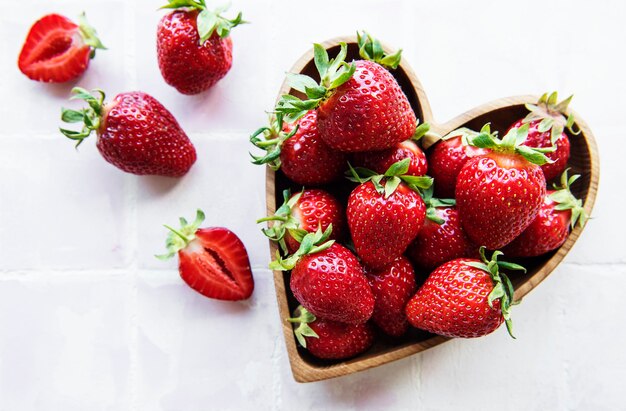 Fresas deliciosas maduras frescas en un tazón de madera en forma de corazón