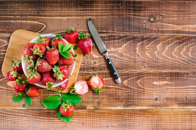 Fresas dulces maduras en un plato blanco sobre el fondo de madera. copia espacio