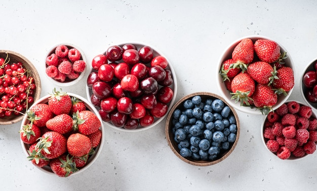 Fresas, frambuesas, arándanos, cerezas, grosellas sobre fondo blanco.