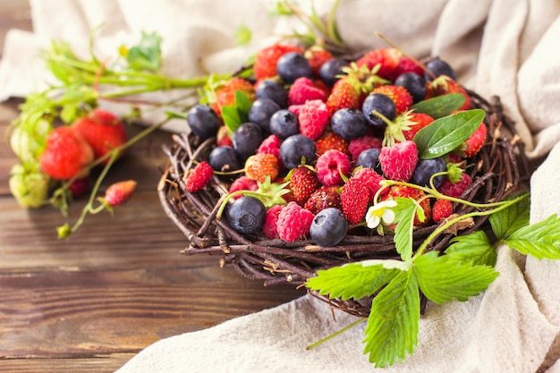 Fresas fresas frambuesas y arándanos sobre un fondo de madera comida sana superalimento ...