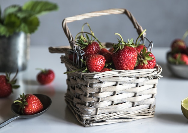 Fresas frescas en una canasta sobre una mesa de madera blanca