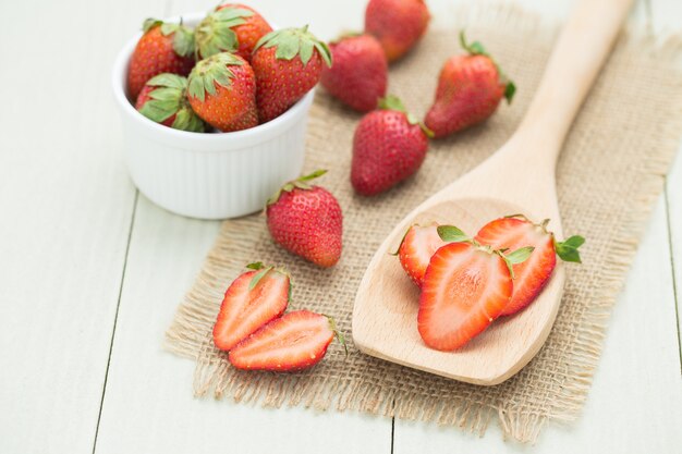 Fresas frescas en una cuchara de madera en la mesa de madera