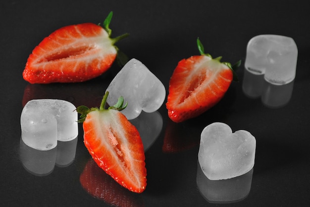 Fresas frescas y hielo en negro con reflejo
