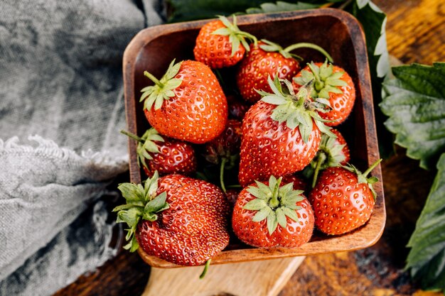 Fresas frescas y jugosas con hojas sobre un fondo de madera