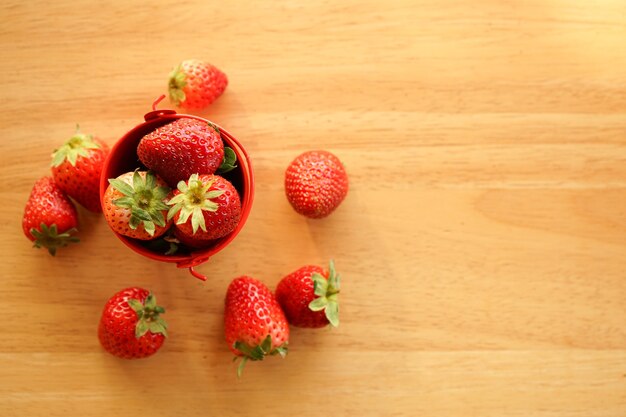 Fresas frescas en un pequeño cubo de agua de acero inoxidable en un escritorio de madera con espacio de copia