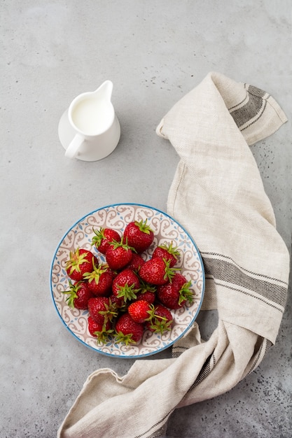 Fresas frescas en placa de luz sobre hormigón viejo gris