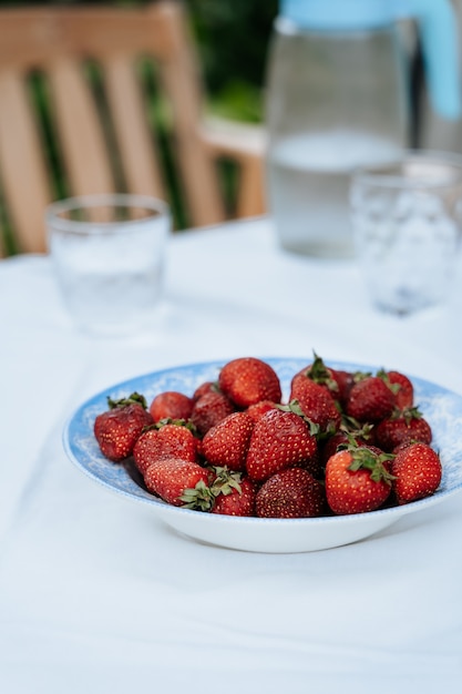 Foto fresas frescas en un plato sobre una mesa de jardín que se sirve para el desayuno vista de cerca