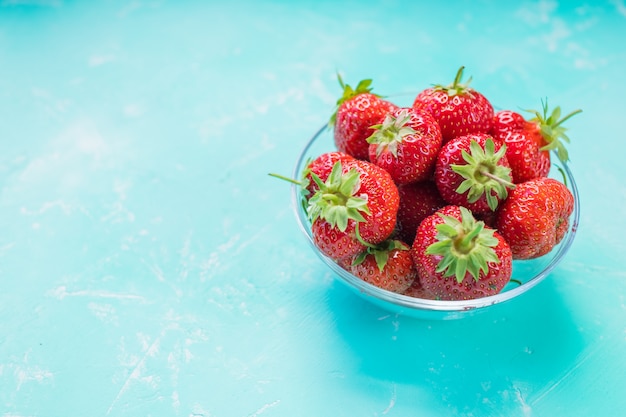 Fresas frescas en un recipiente aislado en azul suave.