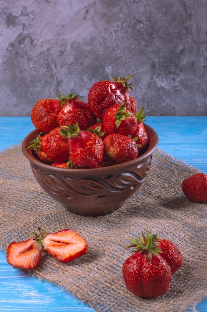 Fresas frescas en un recipiente de arcilla sobre una mesa