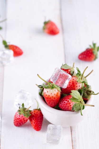 Fresas frescas en un recipiente sobre la mesa de madera