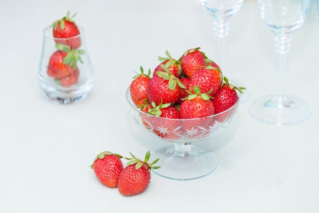 Fresas frescas en recipiente de vidrio sobre fondo blanco.