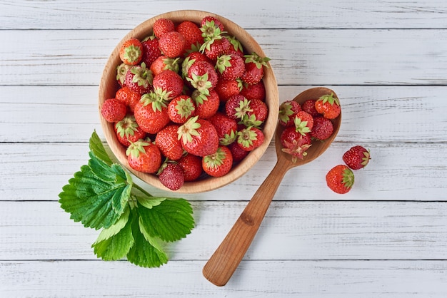 Fresas frescas en un tazón de madera y una cuchara, vista superior