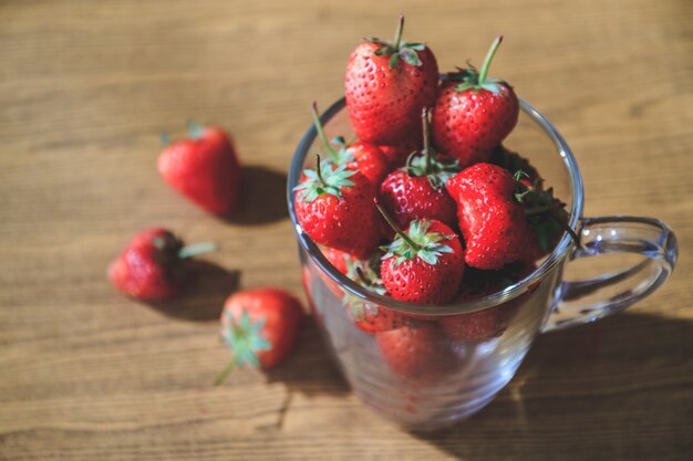 Fresas frescas en vidrio en el fondo de la tabla de madera. Enfoque selectivo