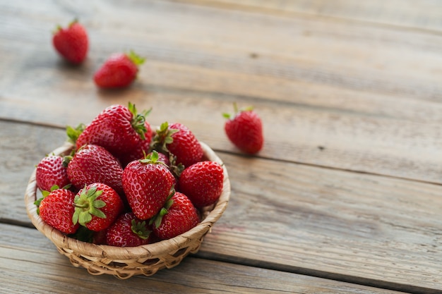 Fresas frescas en la vista superior de la cesta. Comida sana en maqueta de mesa de madera