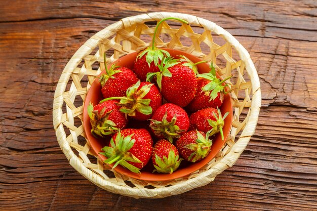 Fresas grandes frescas sobre una mesa de madera en un plato de mimbre. Foto horizontal